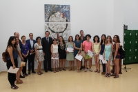 El rector junto a los participantes del concurso que posan delante de la obra ganadora del primer premio